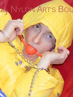 16 of Sonja tied, gagged and hooded on a sofa wearing a sexy blue rain pants and a yellow downwear jacket