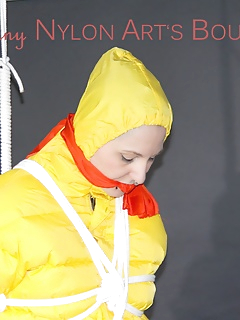 16 of Mara wearing a sexy black rain pants, red rubber boots and a yellow down jacket tied and gagged with ropes and a cloth gag on the ceiling